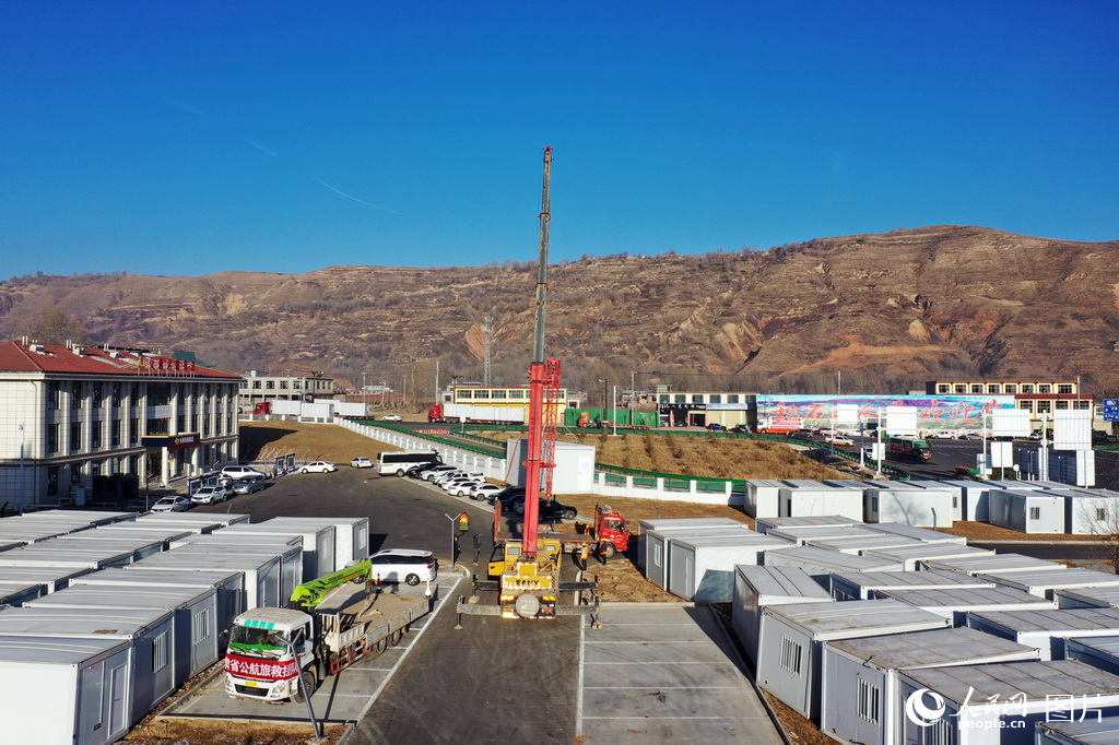 12月26日,甘肃省积石山县高速公路出口附近,甘肃公航旅集团正在转运板房到柳沟乡。