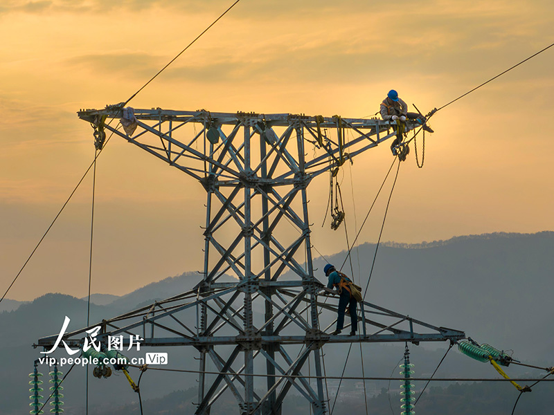 2024年1月5日,在安徽省铜陵市枞阳县横埠镇境内,电力施工人员在30多米高空开展放线安装作业。